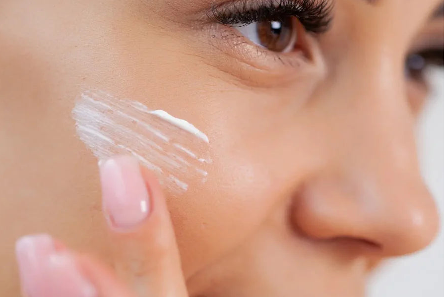 Woman applying sunscreen to her face with a close-up focus.
