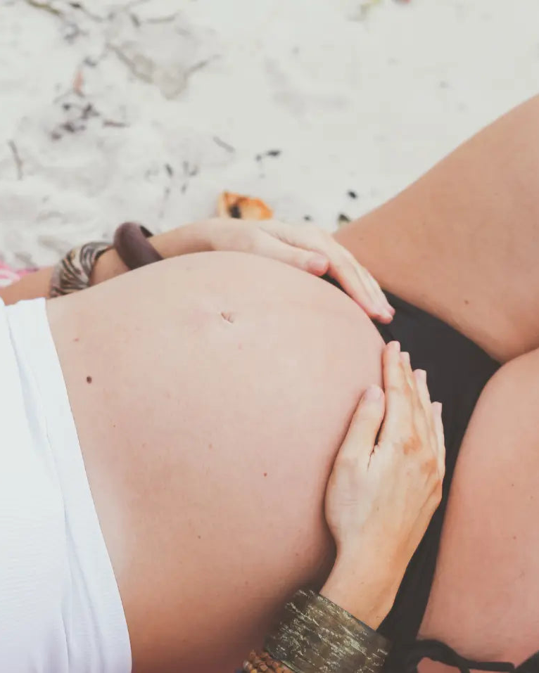 Pregnant woman relaxing on the beach, highlighting AussieZinc Baby SPF50 Mineral Zinc Sunscreen as a safe, organic, and gentle option for pregnancy and delicate skin.